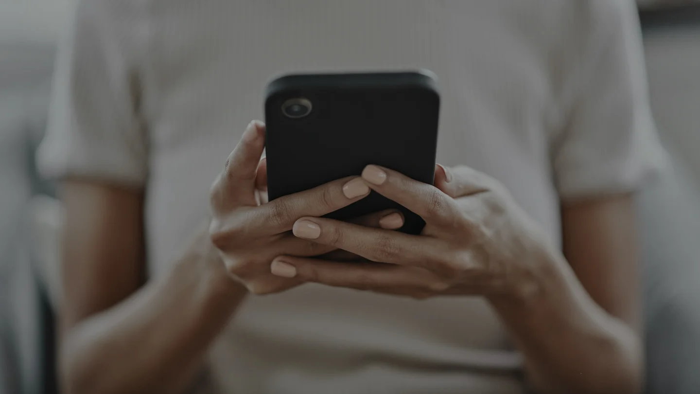 A woman cradling her phone in both hands